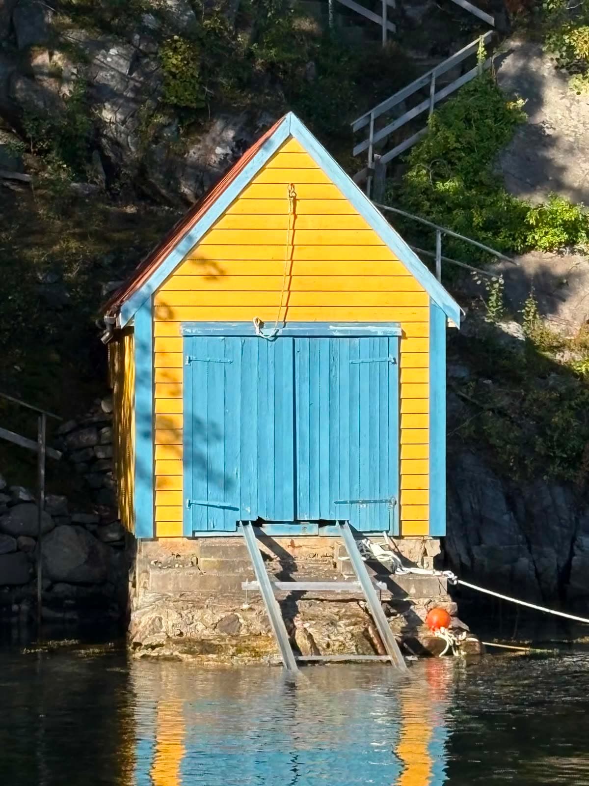 Gult naust med skinner ned i sjøen på Knappskog